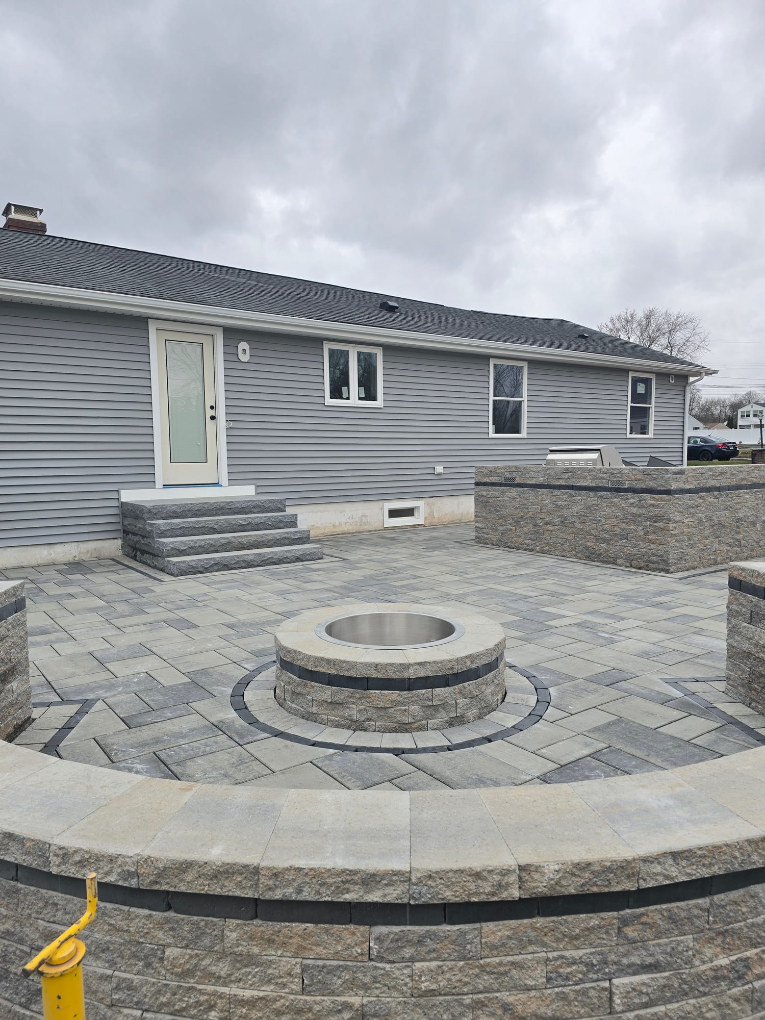 Backyard patio with a fire pit and grill wall
